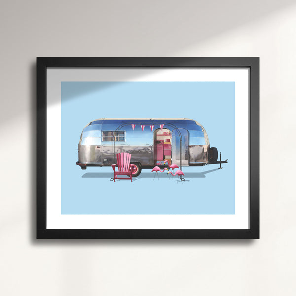 Framed artwork of a vintage 1948 Airstream Liner Camping Trailer with pink chairs and flamingos on a light blue background.