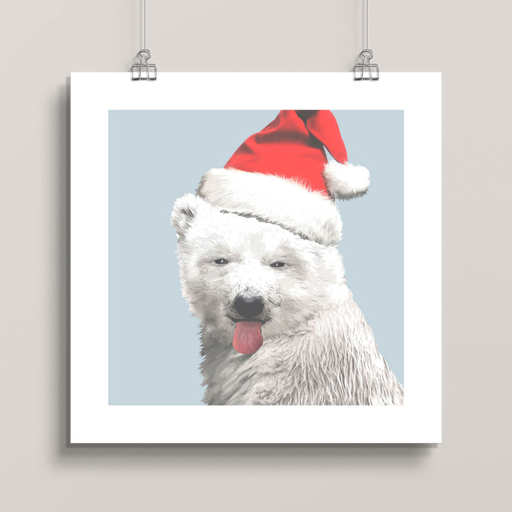Hanging artwork of a polar bear wearing a Santa hat against a light blue background titled North Pole-r Bear