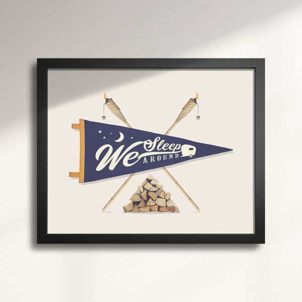Framed wall artwork with a blue pennant, crossed sticks, and woodpile on a light background titled We Sleep Around