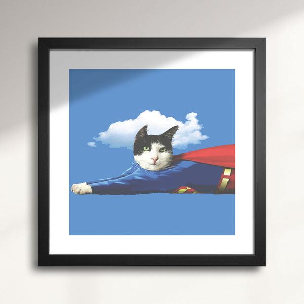 Framed artwork of a cat in a Superman costume against a blue sky with a white cloud titled Super Cat
